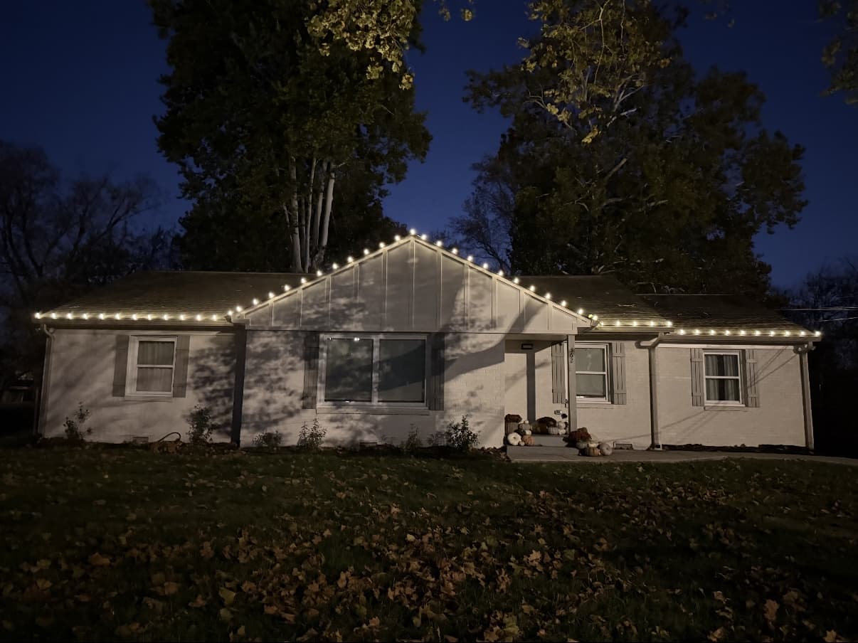 Brick ranch home entry with wreath and roofline lighting