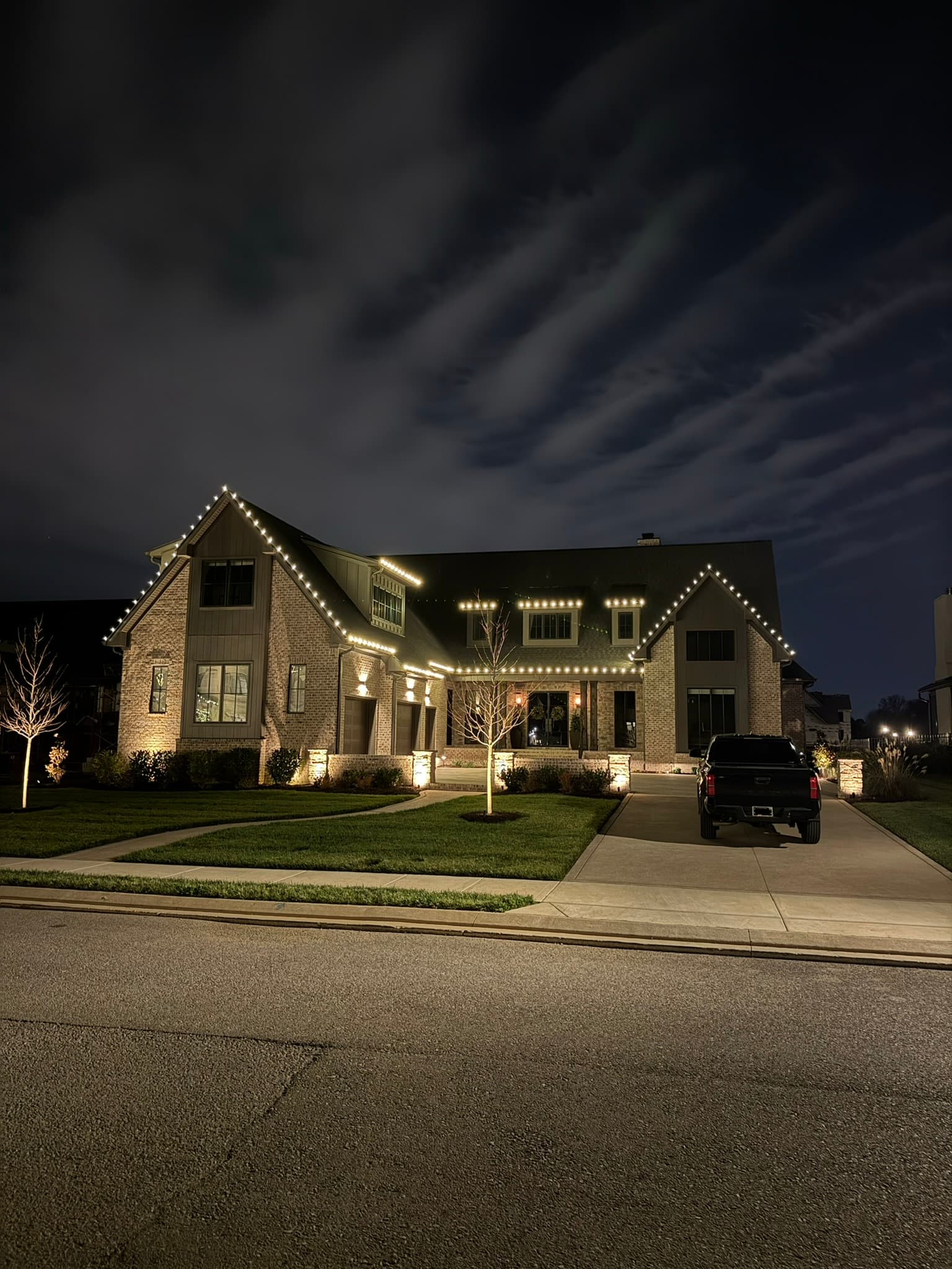 Large two-story brick home with full roofline C9 lighting at dusk