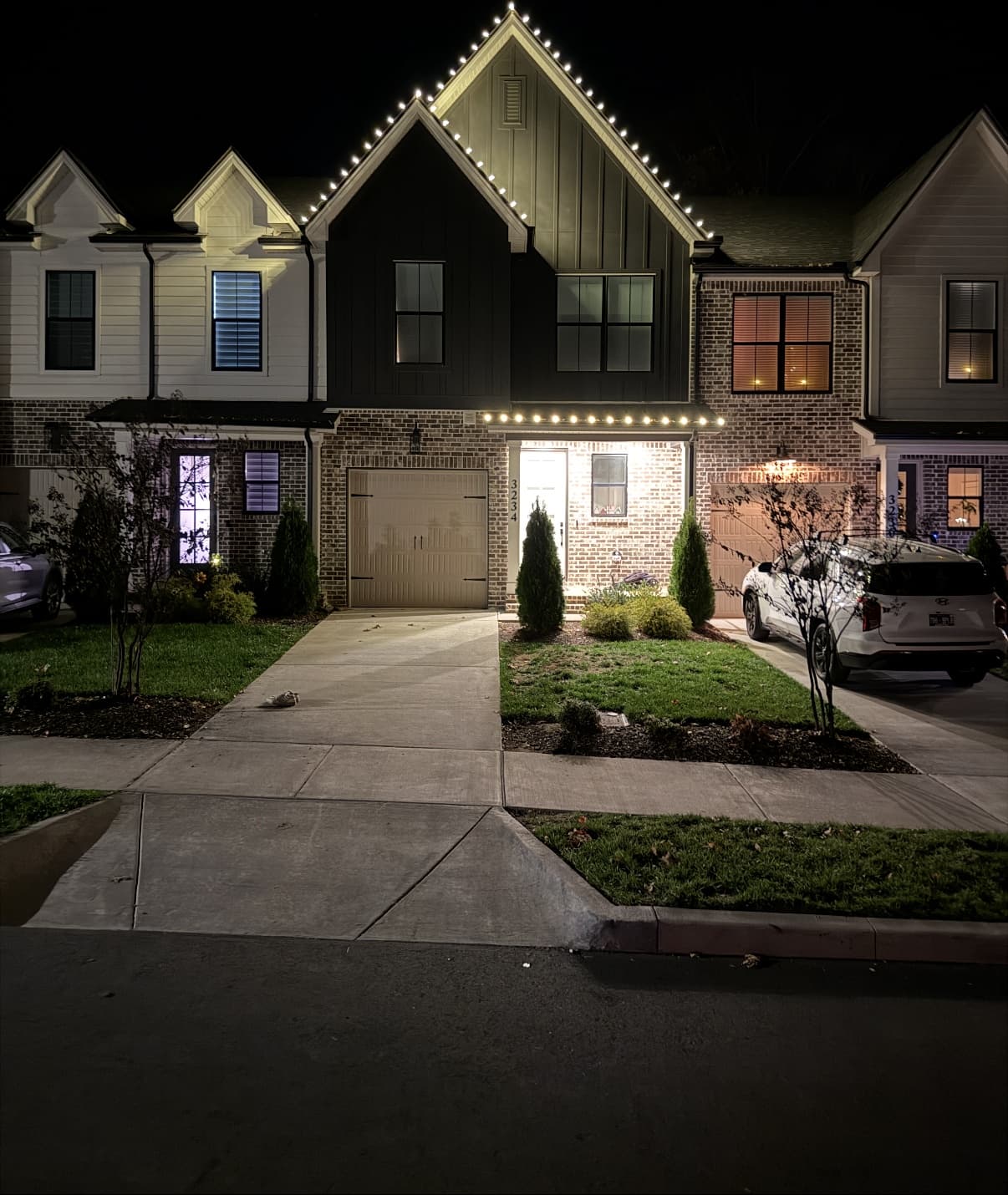 Modern townhome with contrasting black and brick facade, roofline lighting